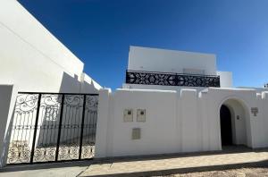 biały budynek z bramą i balkonem w obiekcie Dar El Kahina Djerba w mieście Mezraya