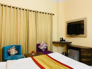 Habitación de hotel con 1 cama y 2 sillas en Hotel Aachman Regency with Rooftop Terrace, en Shimla