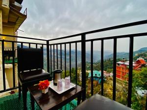 a chair and a table on a balcony with a view at Hotel Aachman Regency with Rooftop Terrace in Shimla