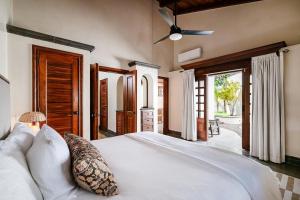 a bedroom with a white bed with a ceiling fan at Casa Libelula in Tamarindo