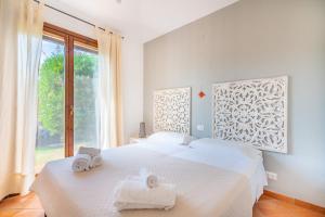 una camera bianca con due letti e una finestra di Splendida Villa a Notteri, Spiaggia di Porto Giunco a Notteri
