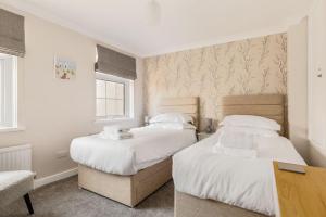 2 bedden in een kleine kamer met witte lakens bij Edward Cottage in Poole