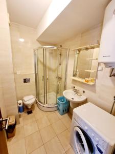 ein Badezimmer mit einer Dusche, einem Waschbecken und einer Waschmaschine in der Unterkunft Centar New Loki Apartments in Budva