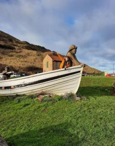 un bateau blanc assis sur une pelouse dans l'établissement Mad Alice's Cottage, à Loftus