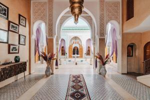 an ornate hallway with a large arched entryway with vases at Palais Alcazar in Marrakech