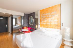- une chambre avec un lit blanc et une grande peinture murale dans l'établissement N’vY Manotel, à Genève