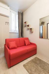 ein rotes Sofa im Wohnzimmer mit Fenster in der Unterkunft Reparata- Cozy nest looks for solo traveller in Florenz