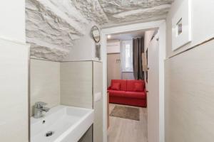 ein Badezimmer mit einem Waschbecken und einer roten Couch in der Unterkunft Reparata- Cozy nest looks for solo traveller in Florenz