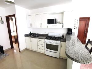 een keuken met witte kasten en een fornuis met oven bij Apartmán Mariscos in Los Corrales