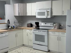 cocina con armarios blancos, fogones y microondas en 13th Floor Apartment with Nice View in Bahía A, en San Juan