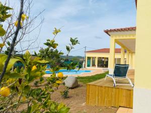 a house with a chair on a deck next to a pool at Pôr-do-sol Villa in São Pedro do Corval