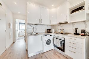 a kitchen with white cabinets and a washer and dryer at Lapa Stylish Apartments in Lisbon