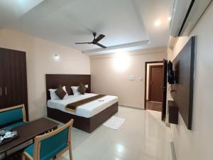 Hotel Classic Comfort في بانغالور: غرفة نوم بسرير وطاولة ومروحة سقف