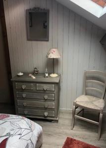 ein Schlafzimmer mit einer Kommode, einer Lampe und einem Stuhl in der Unterkunft Chambre et salle d'eau privées dans maison de ville in La Roche-sur-Yon