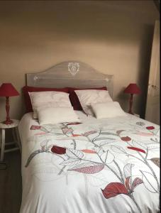 una camera da letto con un letto con copriletto floreale e 2 lampade; di Chambre et salle d'eau privées dans maison de ville a La Roche-sur-Yon