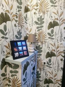 a laptop on a table in a room with wallpaper at La Maison Olivia in La Rivière-Saint-Sauveur