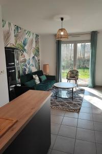sala de estar con sofá verde y mesa en La Maison Olivia, en La Rivière-Saint-Sauveur