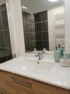 y baño con lavabo blanco y espejo. en La Maison Olivia, en La Rivière-Saint-Sauveur