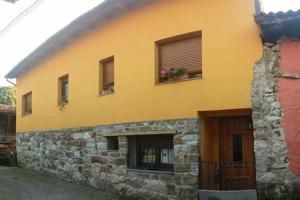 a yellow building with some windows and a door at One bedroom house with wifi at Bermiego in Bermiego