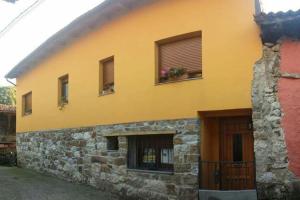un edificio amarillo con algunas ventanas y una puerta en One bedroom house with wifi at Bermiego, en Bermiego