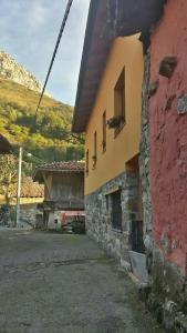un edificio rojo y amarillo junto a una montaña en One bedroom house with wifi at Bermiego, en Bermiego