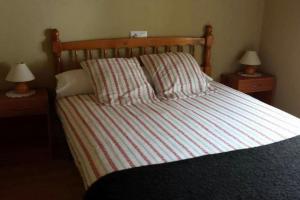 a bed with a striped comforter and two night stands at One bedroom house with wifi at Bermiego in Bermiego