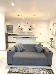 a living room with a couch and a kitchen at Modern apartment, a home away from home right next to the beachfront in Summerstrand