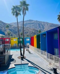 un bâtiment coloré avec des palmiers et une piscine dans l'établissement Delos Reyes Palm Springs, à Palm Springs
