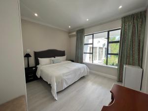 1 dormitorio con cama y ventana grande en Elegant Guest House Sandton, en Johannesburgo