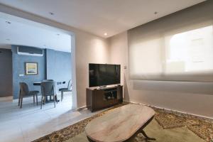 uma sala de estar com uma televisão de ecrã plano e uma mesa em The Place To Be - Agadir Centre em Agadir