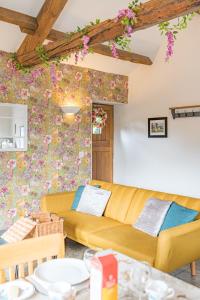 a living room with a yellow couch and a floral wall at The Byre, Melmerby in Gamblesby