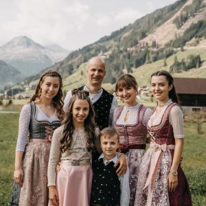 a family posing for a picture with mountains in the background at Hotel Garni Grünmoos in Sankt Jakob in Defereggen