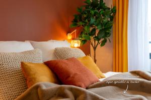 einen Haufen Kissen auf einem Bett mit Pflanze in der Unterkunft Studio Delorme in Bagneux