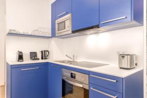 cocina azul con fregadero y microondas en limehome Graz - Argos by Zaha Hadid, en Graz