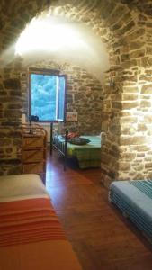 een kamer met 2 bedden en een stenen muur bij B&B Da Marta in Apricale