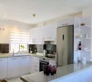 eine Küche mit weißen Schränken und einem Kühlschrank aus Edelstahl in der Unterkunft Aljamar 24 Comfortable house near Burriana Beach in Nerja