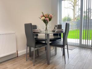 une table à manger avec des chaises et un vase de fleurs dans l'établissement Wembley Stadium, Modern&Cozy Apartment with Garden, à Londres