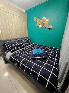 a bedroom with a bed with blue sheets and a green wall at Serenity Cove MOA in Manila