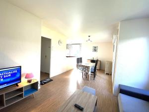 een woonkamer met een televisie en een eettafel bij Charmant appartement rénové à neuf 4 personnes à Hennebont - MATÉO in Hennebont