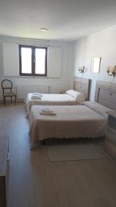 a room with three beds and a chair and a window at Hostal padornelo in Mondoñedo