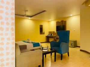 um quarto de hotel com uma cama e uma cadeira azul em Aachman Nature Valley Resort Shimla em Shimla