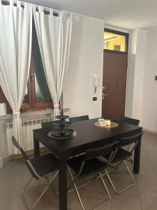 uma mesa preta e cadeiras num quarto com cortinas em modern apartment Legnano em Legnano