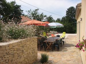 eine Terrasse mit einem Tisch, Stühlen und Sonnenschirmen in der Unterkunft Maison Besun in Dieulefit