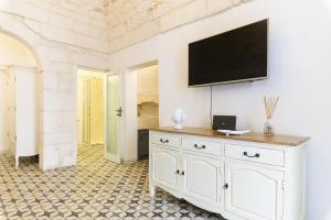 uma cómoda branca com uma televisão de ecrã plano na parede em La Dimora del Tempo by Wonderful Italy em Ostuni