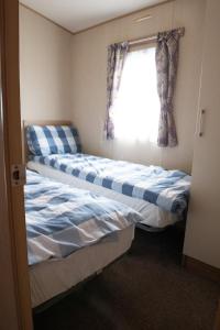 two beds in a small room with a window at 2 Bed Caravan For Hire at Golden Sands in Rhyl in Rhyl