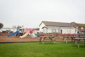 a playground with wooden benches and a play area at 2 Bed Caravan For Hire at Golden Sands in Rhyl in Rhyl
