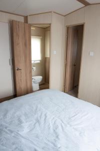 a bedroom with a white bed and a toilet at 2 Bed Caravan For Hire at Golden Sands in Rhyl in Rhyl