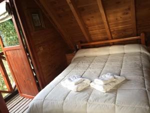 Una cama en una cabaña con dos toallas. en Cabañas Ruca Nahuel en Villa La Angostura