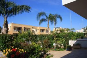 a building with palm trees and flowers in a yard at Villetta con patio e giardino in Gallipoli