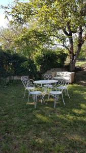 a table and chairs in a field with a tree at Le Pti Clos 